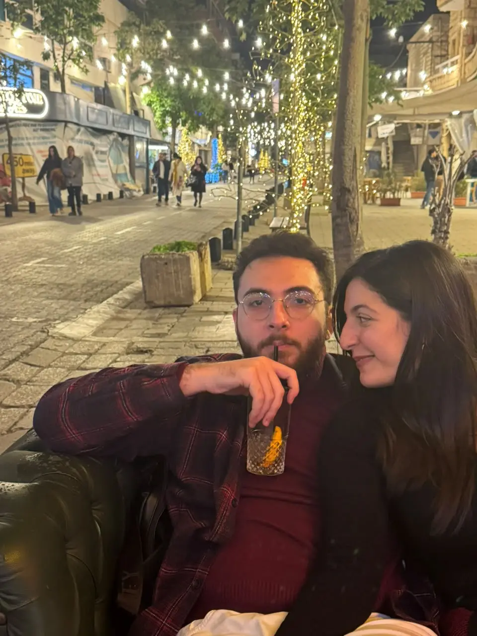 A couple on a bench under string lights