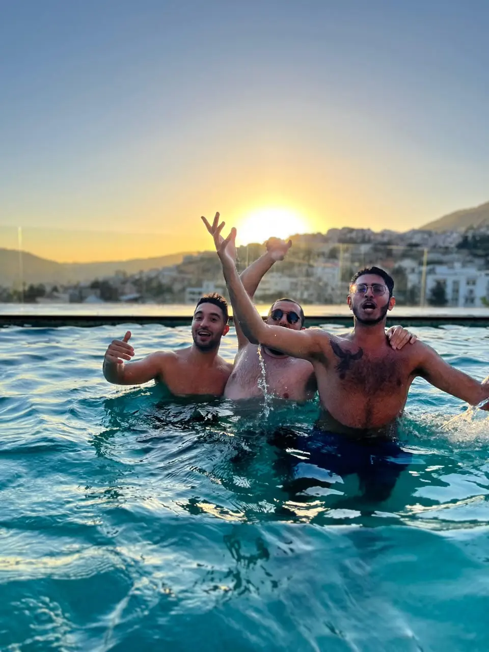 Three friends in a pool at sunset